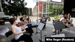 A string quartet of musicians from the New York Philharmonic Orchestra perform across from David Geffen Hall at Lincoln Center, in their first public performance since the Orchestra's closing in March due to the COVID-19 outbreak in New York City, New York, U.S., July 7, 2020.