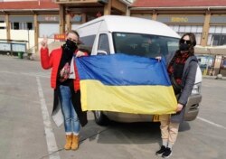 CHINA -- Ukrainian passengers hold Ukrainian flag as they pose for photo before boarding the aircraft chartered by Ukrainian government to evacuate 45 Ukrainian and 27 foreign citizens from Wuhan, February 19, 2020