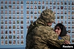 A Ukrainian serviceman hugs a woman as they visit the Wall of Remembrance in Kyiv to pay tribute to killed Ukrainian servicemen during a commemorative ceremony to mark the Volunteer Day on March 14, 2023. (Gleb Garanich/Reuters)