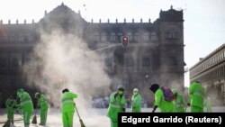MEXICO – Municipal employees work amid a cloud of dust at Zocalo square, in Mexico City on July 20, 2020.