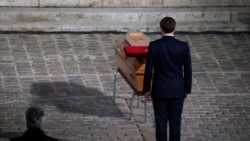 French President Emmanuel Macron pays his respects by the coffin of slain teacher Samuel Paty in the courtyard of the Sorbonne university during a national memorial event, in Paris, France October 21, 2020.