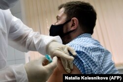 RUSSIA -- A nurse inoculates volunteer Ilya Dubrovin, 36, with Russia's new coronavirus vaccine in a post-registration trials at a clinic in Moscow, Sept. 10, 2020.