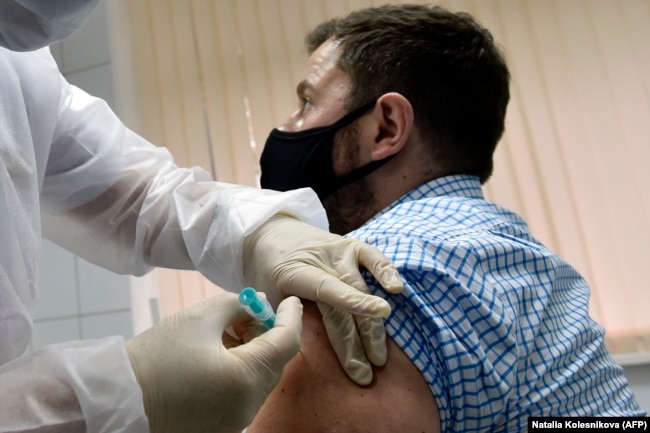 RUSSIA -- A nurse inoculates volunteer Ilya Dubrovin, 36, with Russia's new coronavirus vaccine in a post-registration trials at a clinic in Moscow, Sept. 10, 2020.