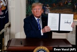 U.S. -- U.S. President Donald Trump shows a signed Presidential Memorandum after delivering a statement on the Iran nuclear deal from the Diplomatic Reception Room of the White House, May 8, 2018