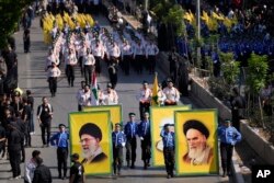 Hezbollah al-Mahdi scouts carry portraits of Iran's late revolutionary founder Ayatollah Khomeini, right, and for the Supreme Leader Ayatollah Ali Khamenei, left, during the holy day of Ashoura that commemorates the 7th century martyrdom of the Prophet Muhammad's grandson Hussein, in the southern suburb of Beirut, Lebanon, on August 9, 2022. (Hussein Malla/AP)
