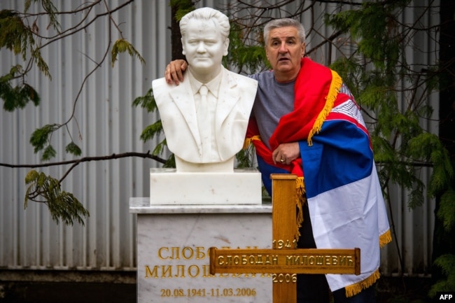 Serbia -- A man poses for a photograph next to the grave of late Yugoslav President Slobodan Milosevic in the town of Pozarevac, March 11, 2016
