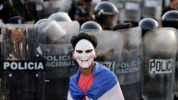 NICARAGUA – A masked youngster protests against Nicaraguan President Daniel Ortega's government in front of a line of riot police blocking a street in Managua, on September 13, 2018.