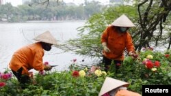 Gardeners wear protective face masks as they work at Hoan Kiem Lake amid the coronavirus disease (COVID-19) outbreak in Hanoi, Vietnam, February 18, 2021. REUTERS/Thanh Hue