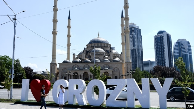 Young people take a photo in front of the Heart of Chechnya - Akhmad Kadyrov Mosque and large letters reading 'I love Grozny' in central Grozny on July 26, 2017. / AFP PHOTO / Kirill KUDRYAVTSEV