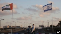Women walk past United Arab Emirates and Israeli flags at the Peace Bridge in Netanya, Israel, Sunday, Aug. 16, 2020. The UAE flag was displayed to celebrate last week's announcement that Israel and the UAE have agreed to normalize relations.