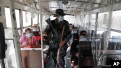 A policeman checks a passenger bus at a checkpoint on the second day of a stricter lockdown to prevent the spread of the coronavirus in the outskirts of Quezon City, Philippines, on March 30, 2021.