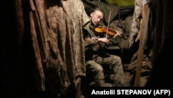 A Ukrainian serviceman plays the violin in the dugout of a position on the front line with Russia-led forces, not far from Horlivka, in the Donetsk region, on December 22, 2020.