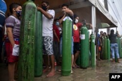 Relatives of COVID-19 patients queue for long hours to refill their oxygen tanks in Manaus, Amazonas state, on January 19, 2021. (AFP)
