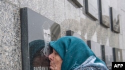 A Kosovo Albanian woman, Vezire Gjeladini, kisses the picture of her son etched into a commemorative plaque and placed on a wall dedicated to the victims of the 1999 Racak massacre on January 15, 2018. (Armend Nimami/AFP)