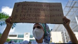 A nurse holds a sign reading "Vaccines without exclusion. Let's stop counting the dead. Let's start counting the vaccinated," during protest in Caracas, on April 17, 2021.