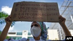 A nurse holds a sign reading "Vaccines without exclusion. Let's stop counting the dead. Let's start counting the vaccinated," during protest in Caracas, on April 17, 2021.