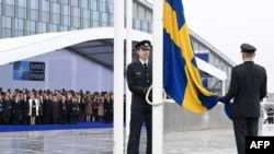 Officials hoist the Swedish national flag on a pole during a flag raising ceremony for Sweden's accession to NATO at the North Atlantic Alliance headquarters in Brussels, on March 11, 2024.