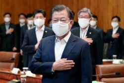 South Korean President Moon Jae-in wearing a mask salutes to a national flag at an emergency meeting on economic response to the coronavirus outbreak at the Presidential Blue House in Seoul, March 30, 2020