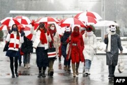 Women wearing carnival masks march carrying umbrellas with the colors of the former white-red-white flag of Belarus to protest against the August 9, 2020, presidential election results in Minsk, Belarus on January 26, 2021.