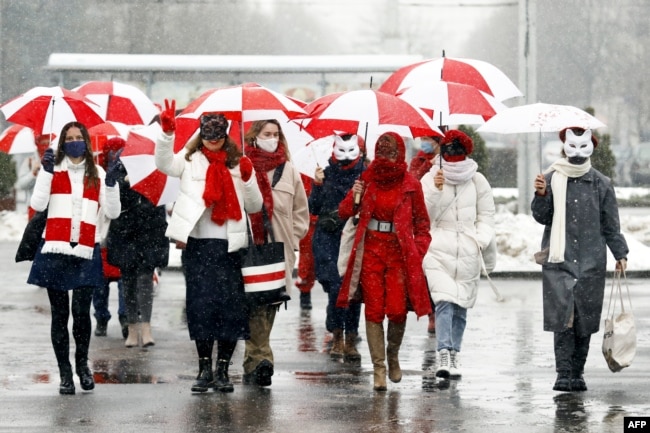 Women wearing carnival masks march carrying umbrellas with the colors of the former white-red-white flag of Belarus to protest against the August 9, 2020, presidential election results in Minsk, Belarus on January 26, 2021.