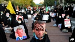 Iranian protesters hold defaced pictures of French President Emmanuel Macron during a protest against the publishing of caricatures of the Prophet Muhammad they deem blasphemous, in front of French Embassy in Tehran, Oct. 28, 2020. (AP/Ebrahim Noroozi)
