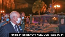 A picture provided by the Tunisian presidency Facebook page on July 26, 2021, shows Tunisian President Kais Saied walking past a military vehicle in Tunis's central Habib Bourguiba Avenue.