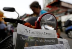 A woman buys the final issue of The Cambodia Daily newspaper at a store along a street in Phnom Penh on September 4, 2017. (Samrang Pring/Reuters)