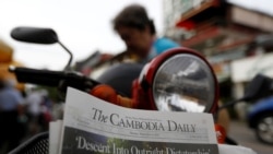 A woman buys the final issue of The Cambodia Daily newspaper at a store along a street in Phnom Penh on September 4, 2017. REUTERS/Samrang Pring