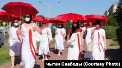 Women with white-red-white umbrellas symbolizing the colors of the Belarusian opposition march in Minsk on June 21, 2021. 