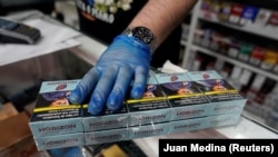 An employee of a tobacco shop sells cigarettes in the Vallecas neighborhood, Madrid, Spain, March 13, 2020.