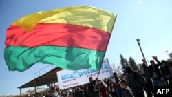 Syria -- A Kurdish man waves a large flag of the Kurdish People's Protection Units (YPG) political wing, the Democratic Union Party (PYD), during a demonstration against the exclusion of Syrian-Kurds from the Geneva talks in the northeastern Syrian city of Qamishli in February 2016.
