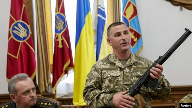 Ukraine -- An Ukrainian military commander (R) shows a rifle seized from Russian soldiers as General Staff commander Viktor Muzhenko looks on during a news conference in Kyiv, May 18, 2015