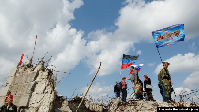 UKRAINE -- Local people hold flags of the self-proclaimed Donetsk Peoples Republic (DPR) and Russia as they stand on the damaged Savur-Mohyla memorial not far from the pro-Russian rebel's controlled Donetsk city, Ukraine, September 7, 2017