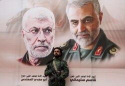 YEMEN -- A Houthi militant stands by a billboard with posters of Iraqi militia commander Abu Mahdi al-Muhandis and Iranian military commander Qassem Soleimani during a rally by Houthi supporters to denounce the U.S. killing of both commanders.
