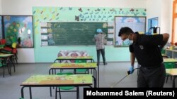 A Palestinian worker wearing a protective face mask sanitizes a classroom in a United Nations-run school before a new academic year starts, amid concerns about the spread of the coronavirus disease (COVID-19), in Gaza City August 4, 2020.