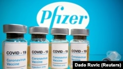 FILE PHOTO: Vials with a sticker reading, "COVID-19 / Coronavirus vaccine / Injection only" and a medical syringe are seen in front of a displayed Pfizer logo in this illustration taken October 31, 2020.