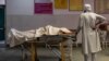 A man stands next to the body of his wife, who died due to breathing difficulties, inside an emergency ward of a government hospital in Bijnor, Uttar Pradesh, India, May 11, 2021. 