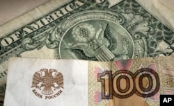 A one hundred rubles banknote is pictured in front of a one US dollar banknote. April 25, 2022. Russia's currency went down and up again since Russia's war in Ukraine and intensified Western sanctions. (AP Photo/Martin Meissner)