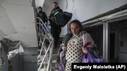 An injured pregnant woman walks downstairs in a maternity hospital severely damaged by bombardment in Mariupol on March 9, 2022. (Evgeniy Maloletka/Associated Press)