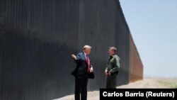 U.S. President Donald Trump talks with U.S. Border Patrol Chief Rodney Scott as he tours a section of the U.S.-Mexico border wall.