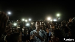A young man, illuminated by mobile phones, reciting protest poetry while demonstrators chant slogans calling for civilian rule, during a blackout in Khartoum, Sudan June 19, 2019. (Reuters)