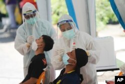 Health workers collect nasal swabs from men for coronavirus testing in Bangkok on Tuesday, June 1, 2021. (AP Photo/Sakchai Lalit)