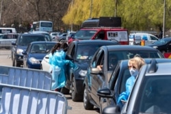 Drivers wait in line to receive a dose of the Pfizer-BioNtech vaccine at a drive-through vaccination cite in Cluj, Romania, on Monday, April 26, 2021.