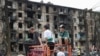 Children look at a rocket-hit apartment building in Kryvyi Rih on June 13, 2023. (Andriy Dubchak/AP)