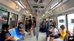 Commuters wear face masks and practice social distancing while onboard a subway on May 19, 2021. Zen Soo/AP