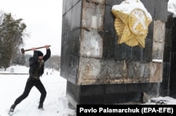 UKRAINE -- A man uses a sledgehammer to damage the Glory Monument in the western of Lviv, February 15, 2018