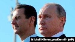 SYRIA -- Russian President Vladimir Putin (R) and Syrian President Bashar Assad watch the troops marching at the Hmeimim military base in Latakia Province, December 11, 2017