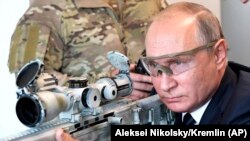 RUSSIA -- Russian President Vladimir Putin aims a sniper rifle during a visit to the Patriot military exhibition center outside Moscow, September 19, 2018