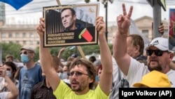 RUSSIA -- A man holds a poster with a portrait of Kremlin critic Aleksei Navalny reading "Navalny was poisoned, we know who is to blame, Aleksei you must live," during an unsanctioned protest in support of regional governor Sergei Furgal in Khabarovsk.