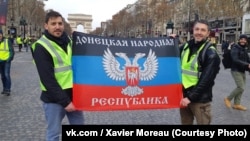  French far-right activists Xavier Moreau (left) and Fabrice Sorlin holding the flag of "DNR" during protests of "yellow vests" in Paris.